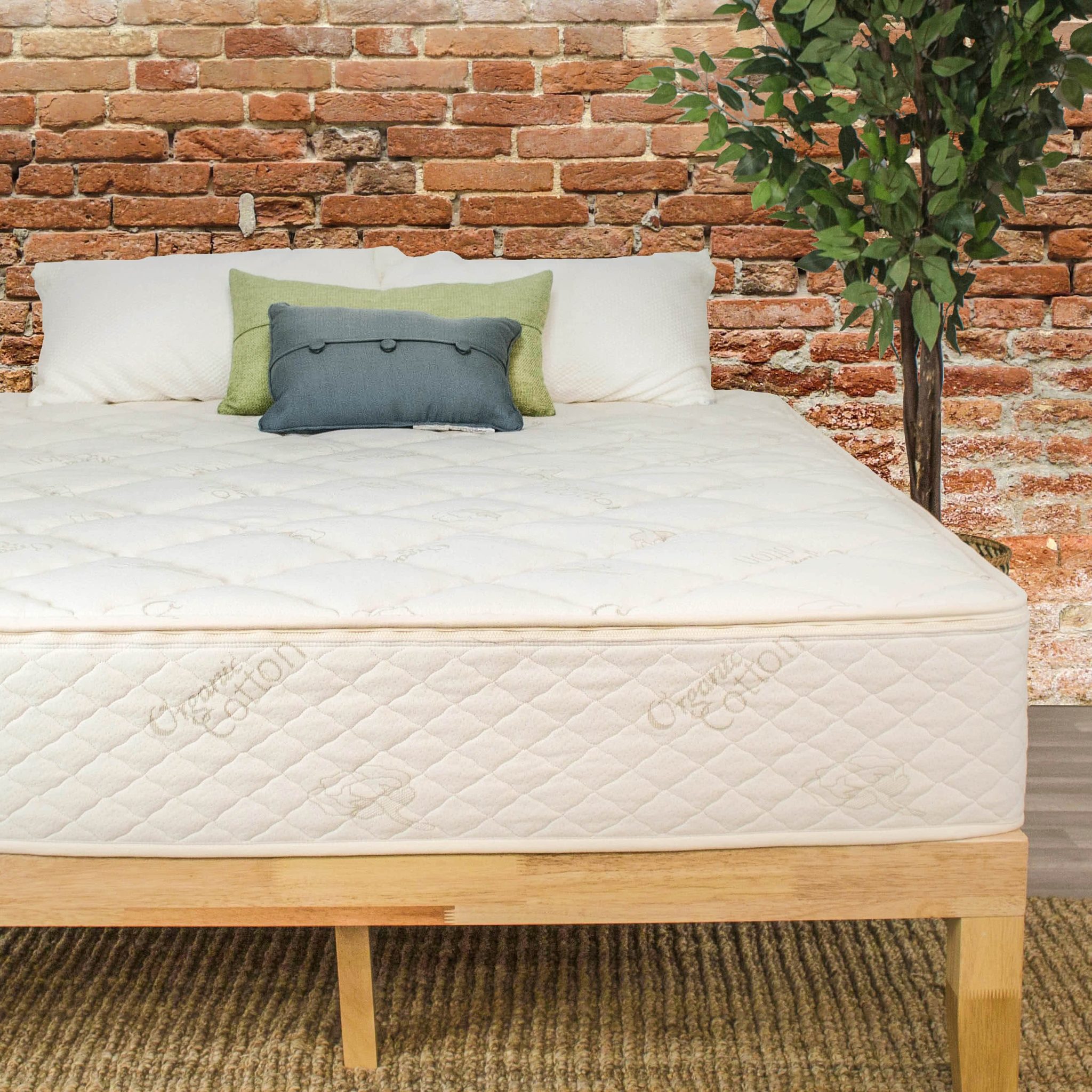 The Natural Latex Mattress by Sleep EZ set up on a wooden bed frame in a room that has a brick wall